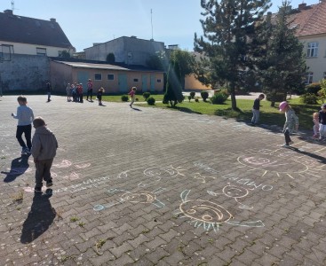 Na zdjęciu dzieci pokonują malowany kredą tor przeszkód. - powiększ