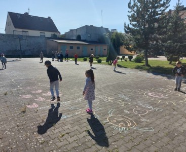 Na zdjęciu dzieci pokonują malowany kredą tor przeszkód. - powiększ