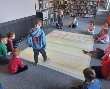 Na zdjęciu przedszkolaki grają w grę interaktywną. - powiększ