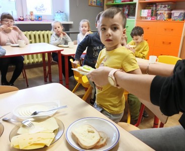 Zdjęcie przedstawia dzieci w trakcie przygotowania kanapki.  - powiększ