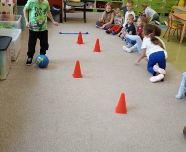 Zdjęcie przedstawia dzieci w trakcie konkurencji sportowych z okazji Dnia Chłopaka. - powiększ