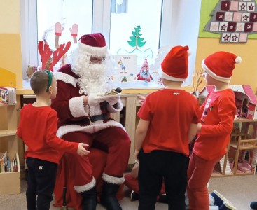 Na zdjęciu dzieci częstują Mikołaja pierniczkami - powiększ