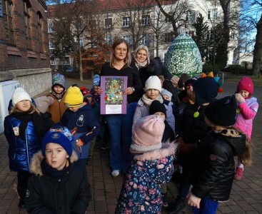 Na zdjęciu dzieci wręczają kartkę bożonarodzeniową  - powiększ