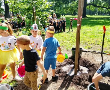 Na zdjęciu dzieci sadzą drzewo z panem burmistrzem. - powiększ