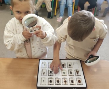 Zdjęcie przedstawia dzieci oglądające okazy przez lupy - powiększ