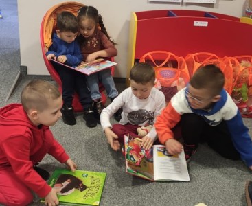 Zdjęcie przedstawia dzieci oglądające książeczki.  - powiększ