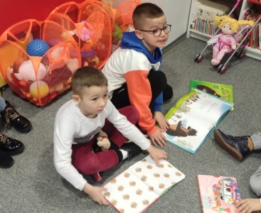 Zdjęcie przedstawia dzieci oglądające książeczki.  - powiększ