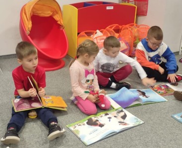 Zdjęcie przedstawia dzieci oglądające książeczki.  - powiększ