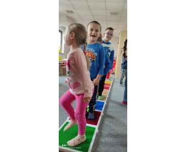 Zdjęcie przedstawia przedszkolaki w trakcie pokonywania toru przeszkód. - powiększ