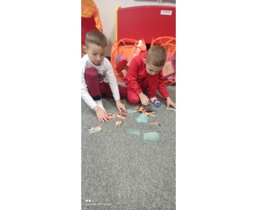 Na zdjęciu ukazano dzieci układające puzzle ,,Misiowe rodzinki'. - powiększ