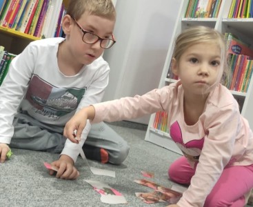 Na zdjęciu ukazano dzieci układające puzzle ,,Misiowe rodzinki'. - powiększ